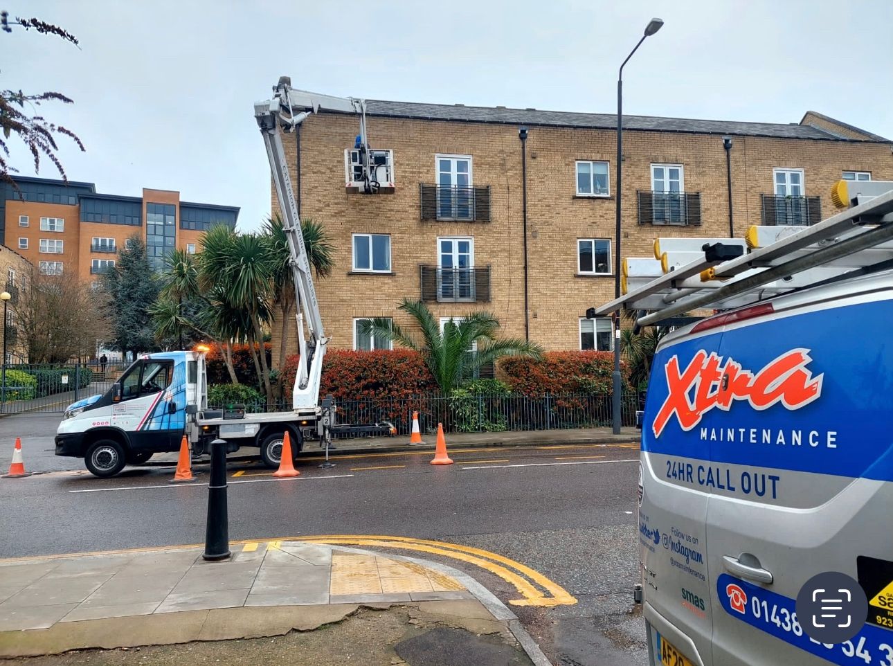 Worker on cherry picker cleaning exterior of building